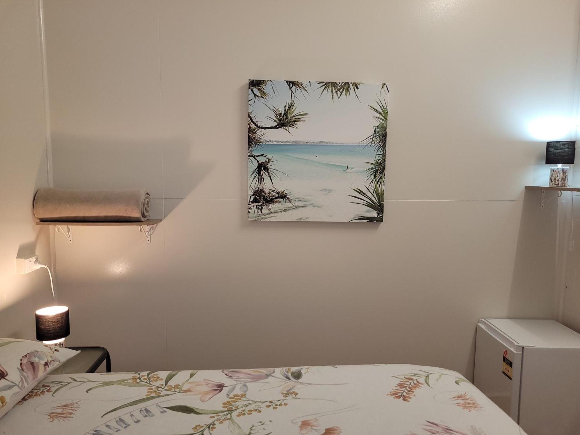 Travellers Paradise Cairns Dış mekan fotoğraf A photograph of a bedroom with a bed, a nightstand, a lamp, a painting, and a television